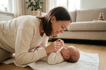 Maman qui éveille doucement son bébé de 1 mois allongé sur une couverture blanche dans un salon scandinave